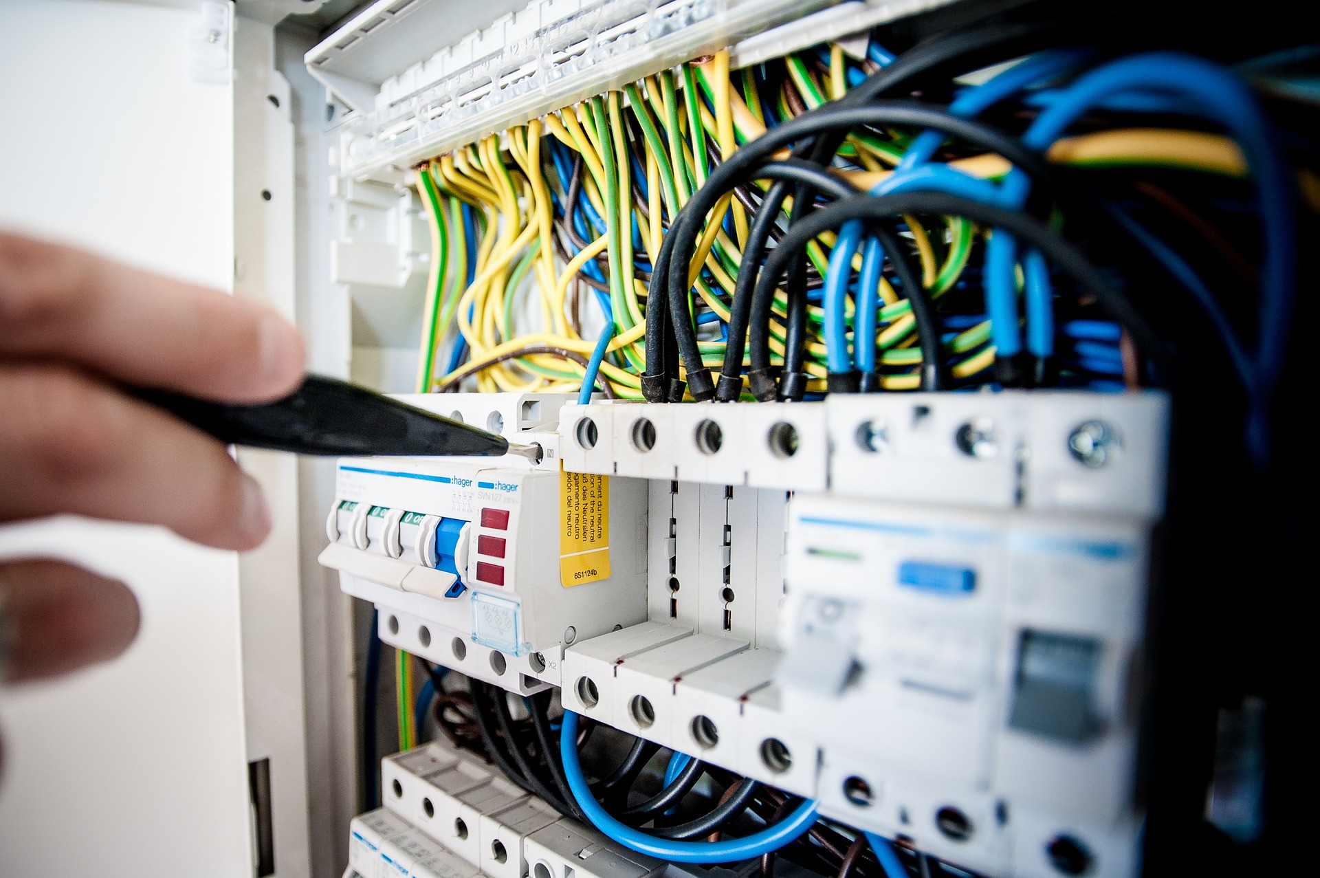 electricien qui travail sur une tableau électrique plein de fils